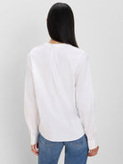 White collarless cotton shirt, back view. Features long sleeves with buttoned cuffs and a central back pleat.