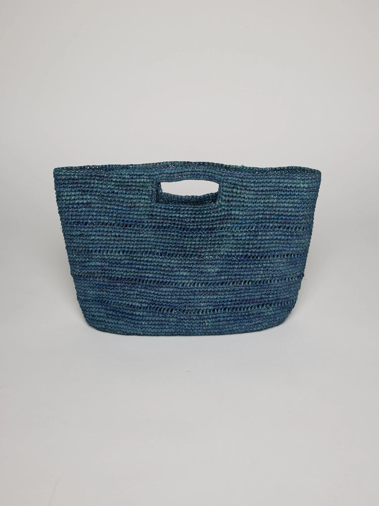 Blue-green woven raffia bag with integrated cut-out handles.
