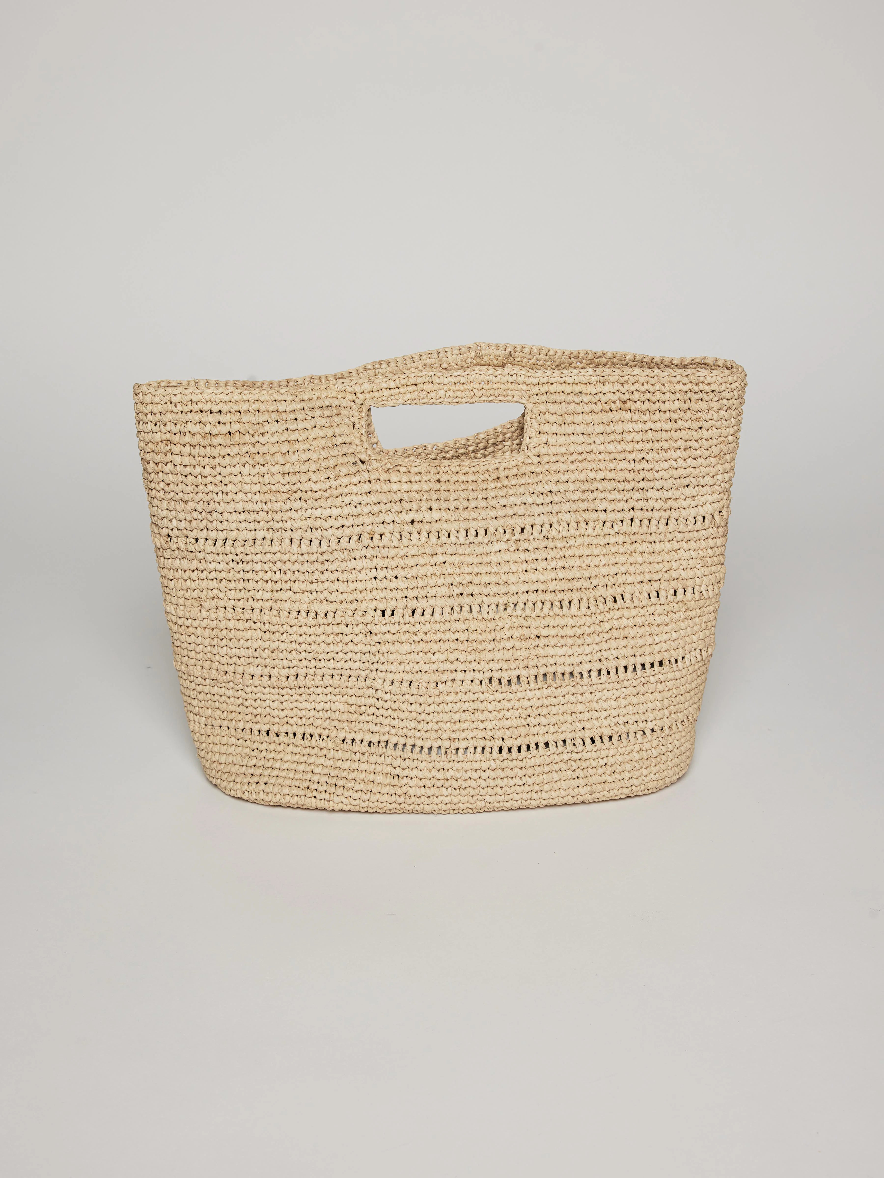 Light beige woven straw handheld bag with integrated cut-out handles and horizontal open weave slits.