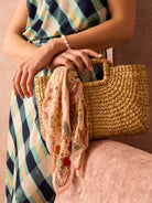 Rectangular woven straw bag in golden tan with a single top handle.