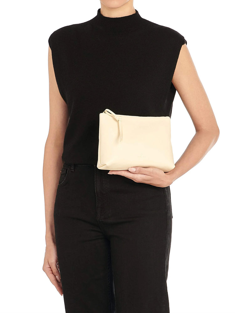 Cream rectangular leather zipper case with a knotted pull, held by a person for scale.