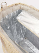 Close-up of straw cooler tote interior: natural woven straw top edge, cream fabric, shiny silver insulated lining &...