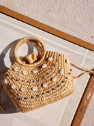 Tan woven straw bag with shell and rhinestone accents.  Top handle.  Light beige drawstring interior.