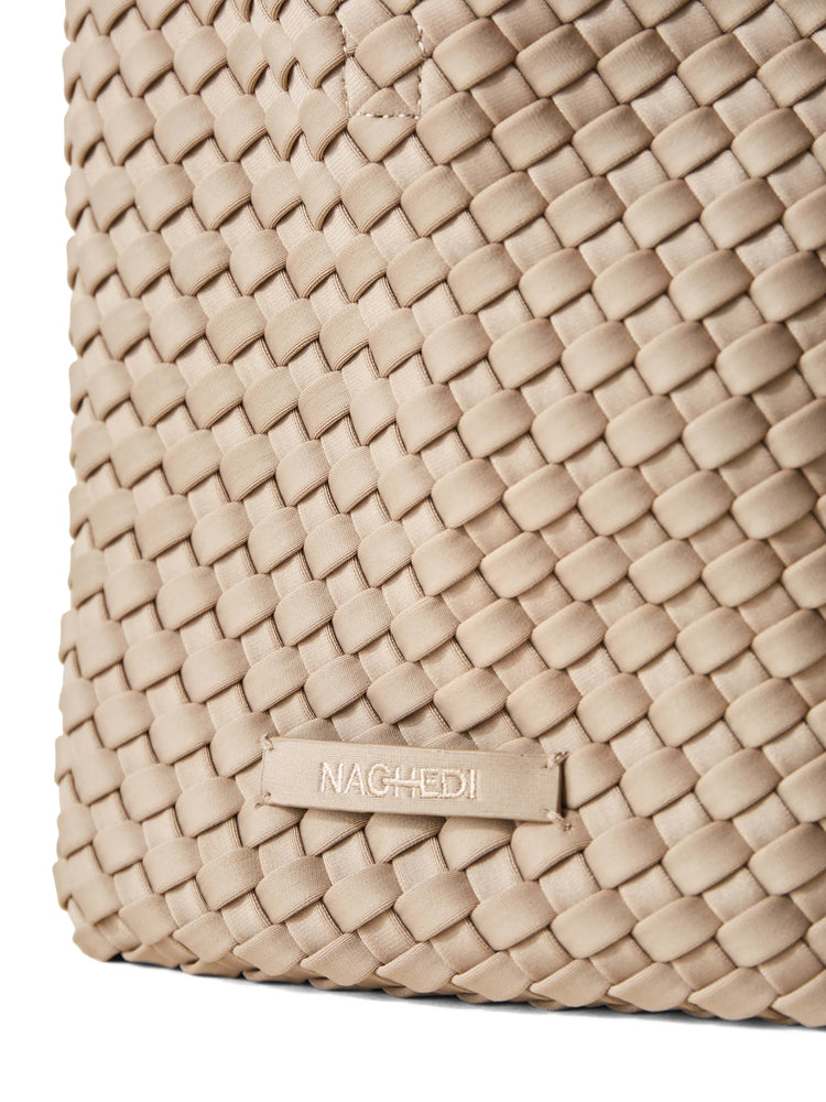 Close-up: light beige Naghedi tote, tightly woven design. "NAGHEDI" embroidered on a small tag.