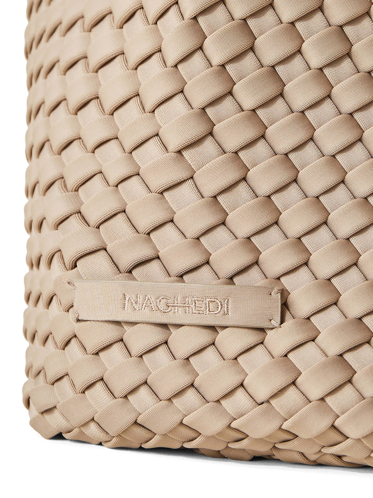 Light tan Naghedi bag, close-up. Features a textured woven pattern and a matching brand tag.
