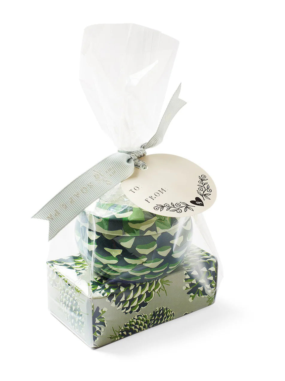 Round candle tin and rectangular soap, both green with a pinecone pattern. Gift-wrapped in clear plastic with a sage...