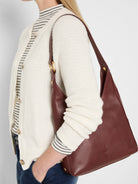 Medium burgundy pebbled leather hobo bag with gold hardware accents and a single shoulder strap.