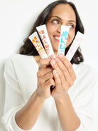 Three white tubes of lip balm with orange, pink, and light blue accents.  "AB LABALM" is printed on each tube.