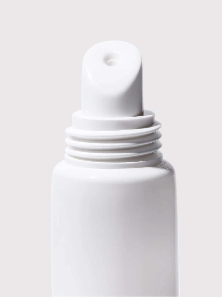 White tube with a slanted, slightly rounded top.  The cap has ridges. Small dispensing hole at the apex.