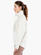 Cream half-zip jacket with high collar, quilted upper chest panel, smooth sleeves, and side pockets.