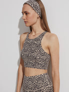A Varley Let's Move Harris Bra, a cropped sports bra with a high neck, featuring a black and beige spotted print.