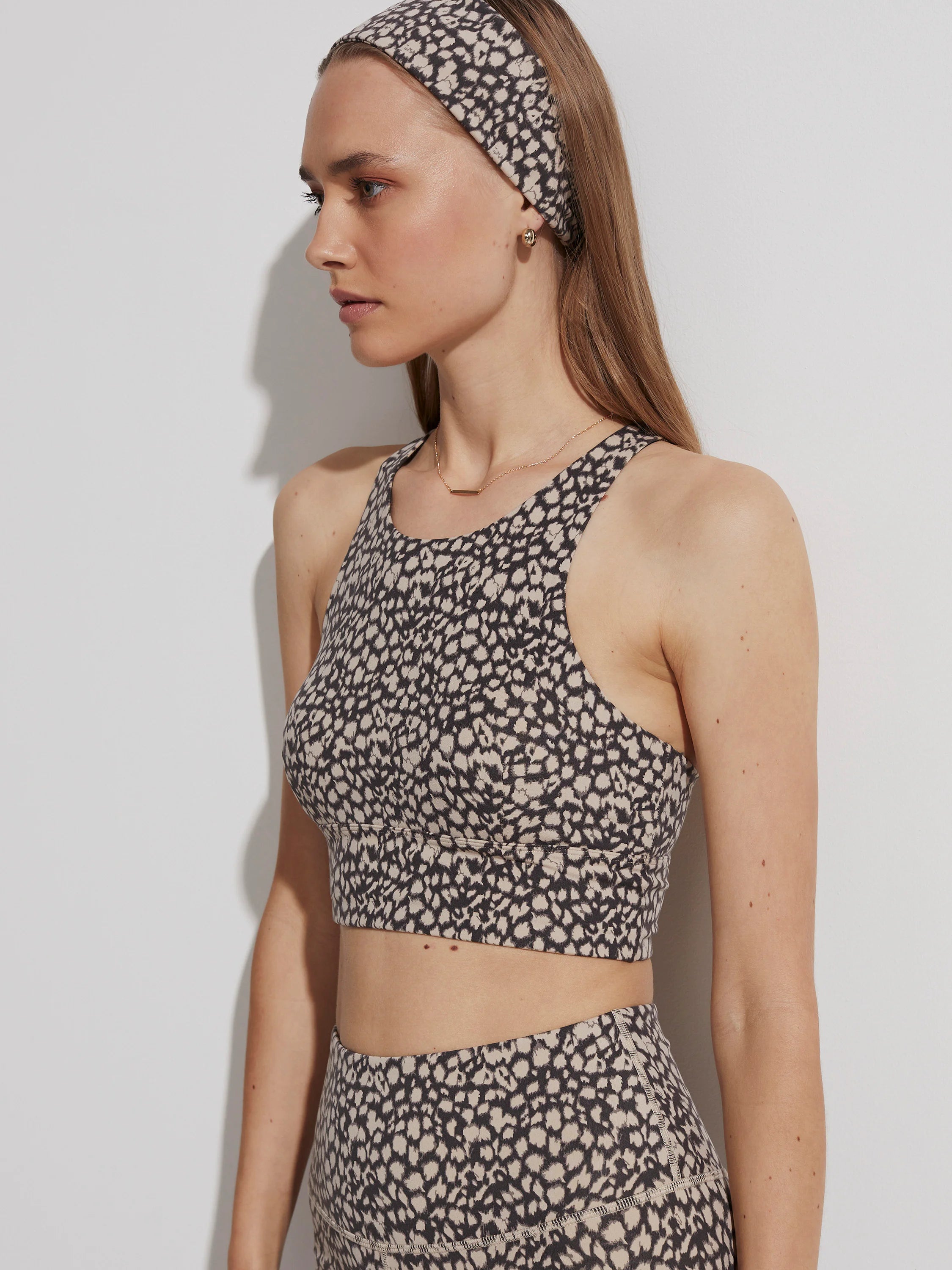 A Varley Let's Move Harris Bra, a cropped sports bra with a high neck, featuring a black and beige spotted print.