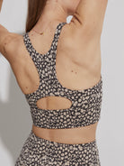 Dark grey and beige speckled sports bra, racerback style with a keyhole cutout on the back.