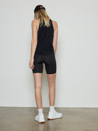Black, mid-thigh length, form-fitting athletic shorts on a model, seen from the back.