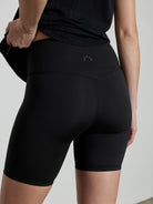 Black, high-waisted athletic shorts, mid-thigh length, with a subtle light grey logo on the back waistband.