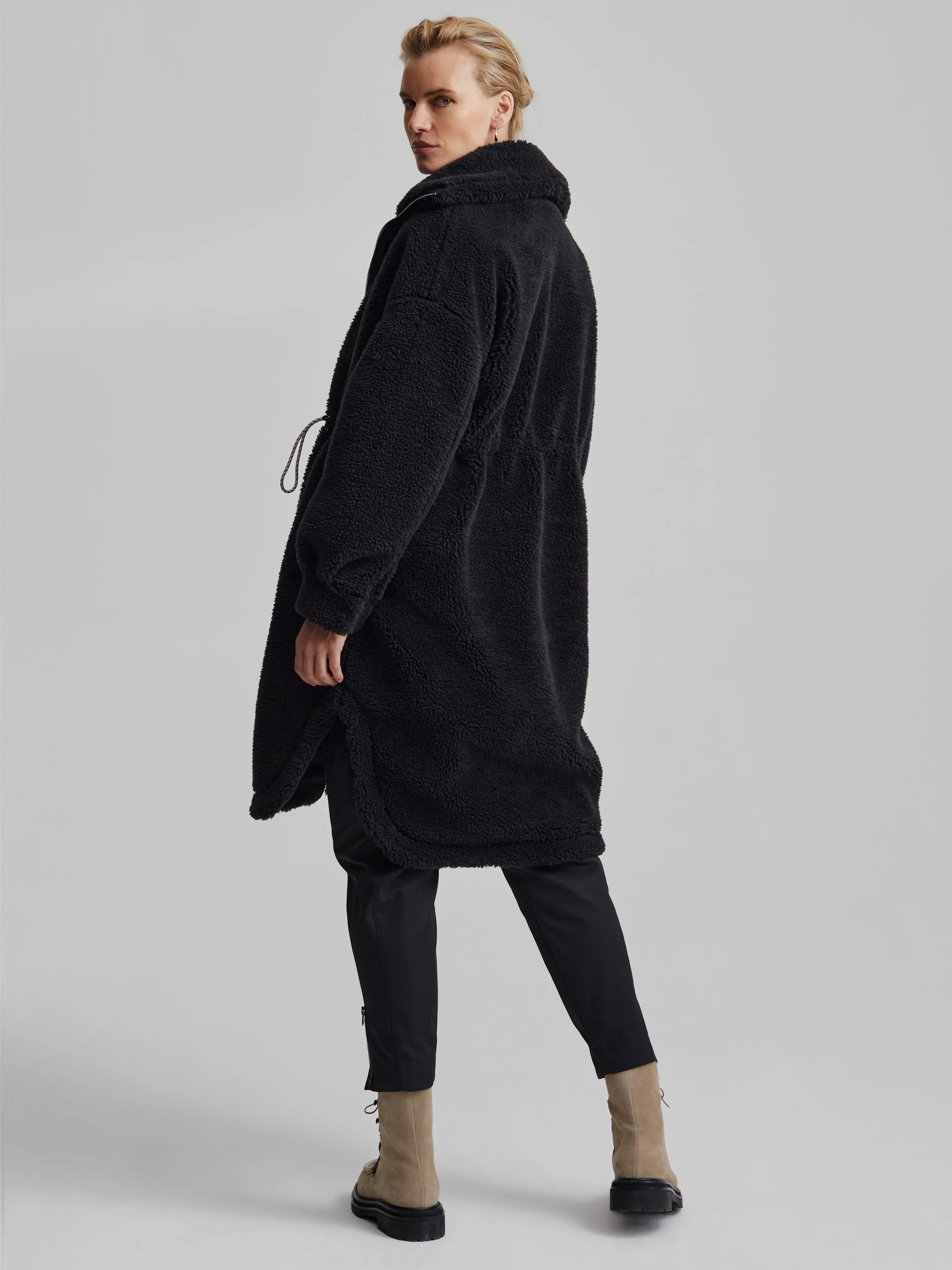 Black long-line teddy fleece coat with a high collar and drawstring waist.