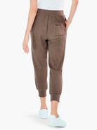 Brown ribbed sweatpants with elasticated waist, ribbed cuffs, and back slit pocket with dark trim, shown from behind.