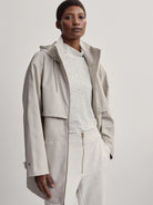Light beige raincoat with a hood and drawstring.  Features a relaxed fit and long sleeves.