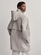 Light grey raincoat featuring an attached hood, high stand collar, and a back storm flap.