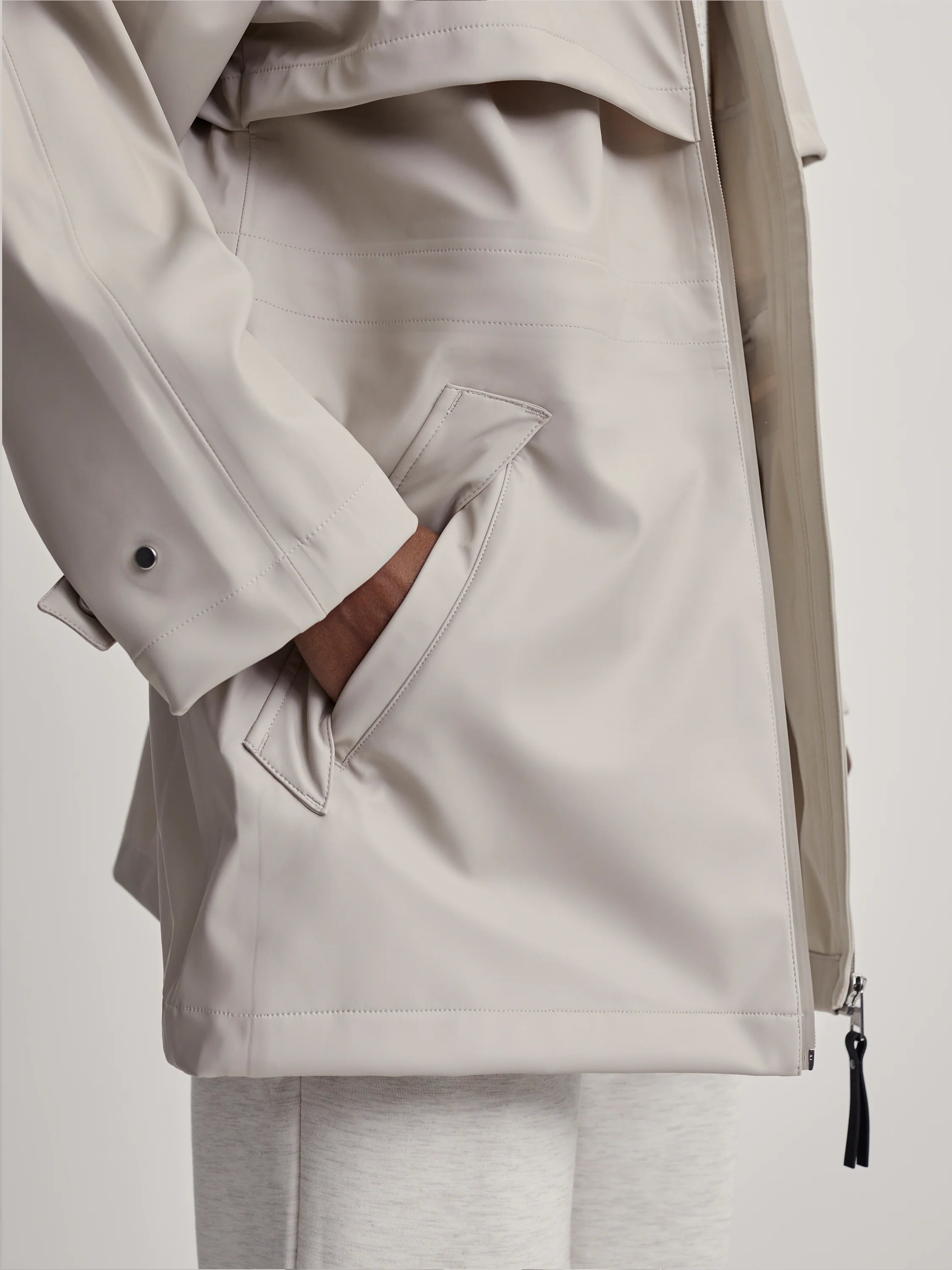 Stone Varley Alyssa Raincoat with a hand in a side pocket, visible stitching, and a black zipper pull.