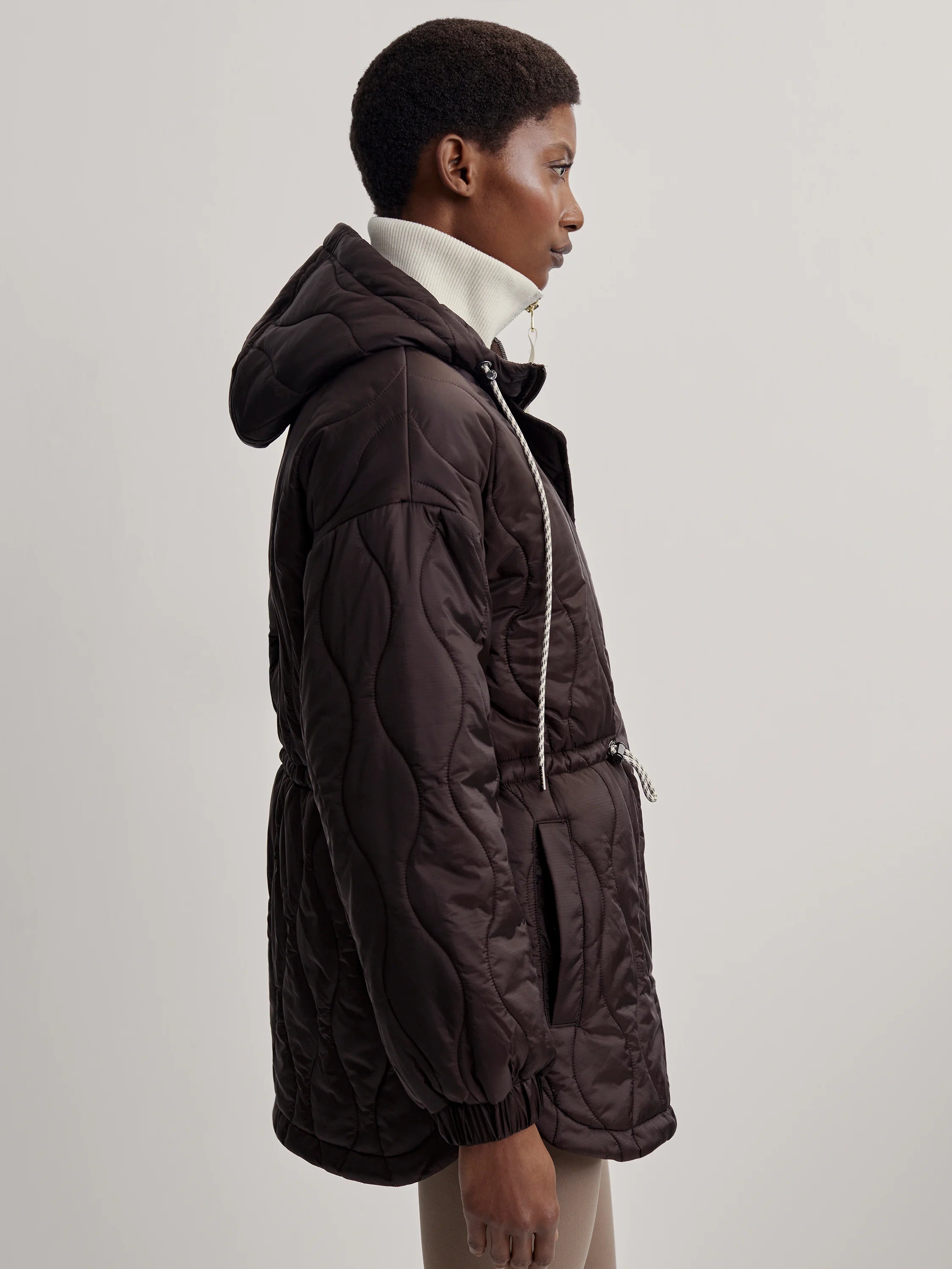 Dark brown quilted jacket with a hood and drawstring waist.  Off-white drawstrings.