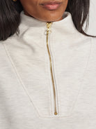 Off-white half-zip sweatshirt with gold zipper.