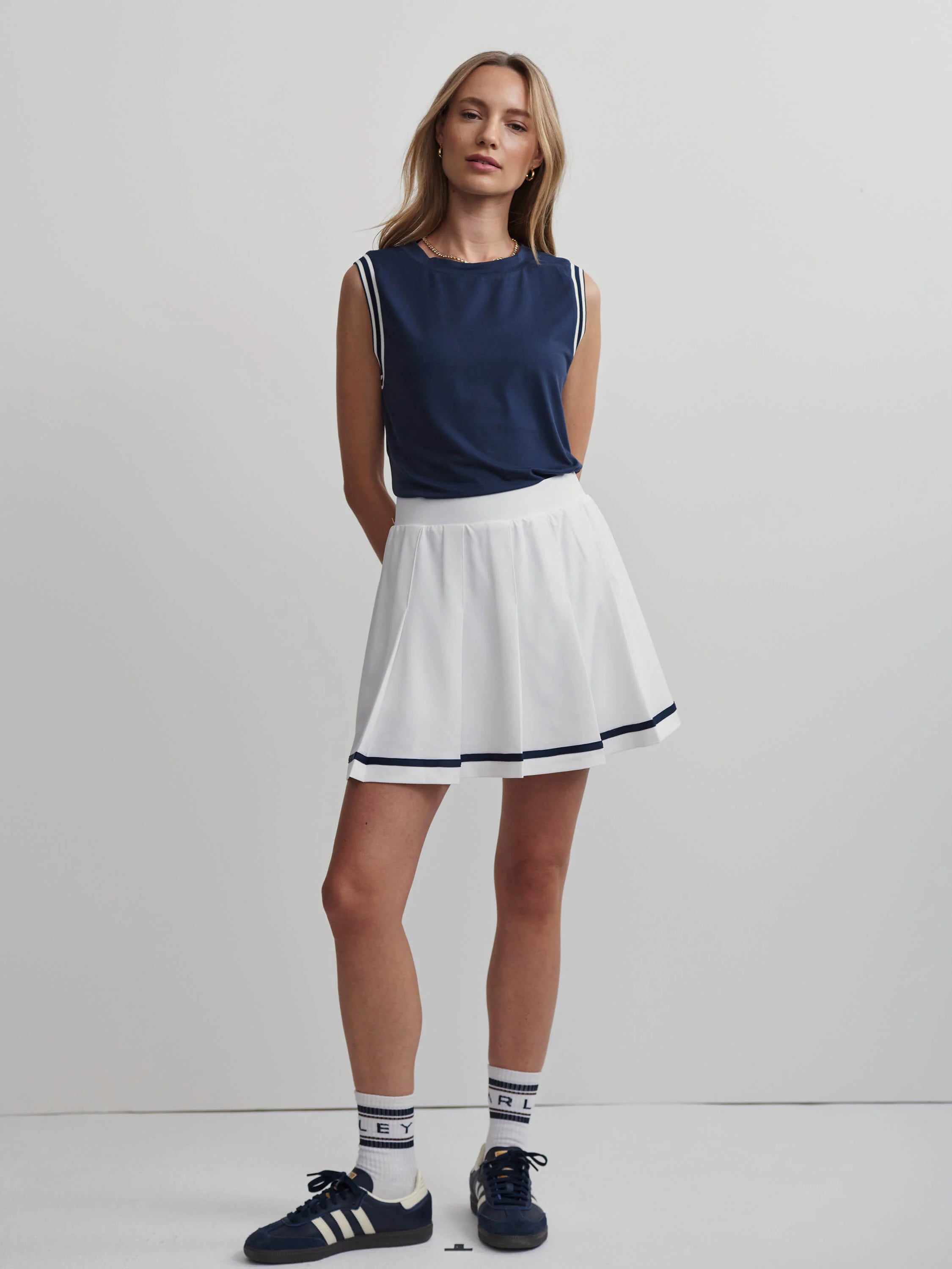 White high-rise pleated skort with a navy blue double stripe detail at the hem.