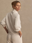 Pale beige heather sweatshirt with mock neck, dropped shoulders, voluminous sleeves, and ribbed cuffs.
