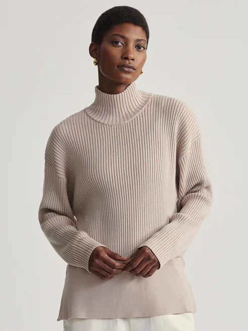 Pale beige mock neck sweater with rib-knit texture. Long sleeves and a relaxed fit.