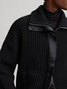 Black heavy rib knit mock neck sweater with silver front zipper and smooth black panel detail.