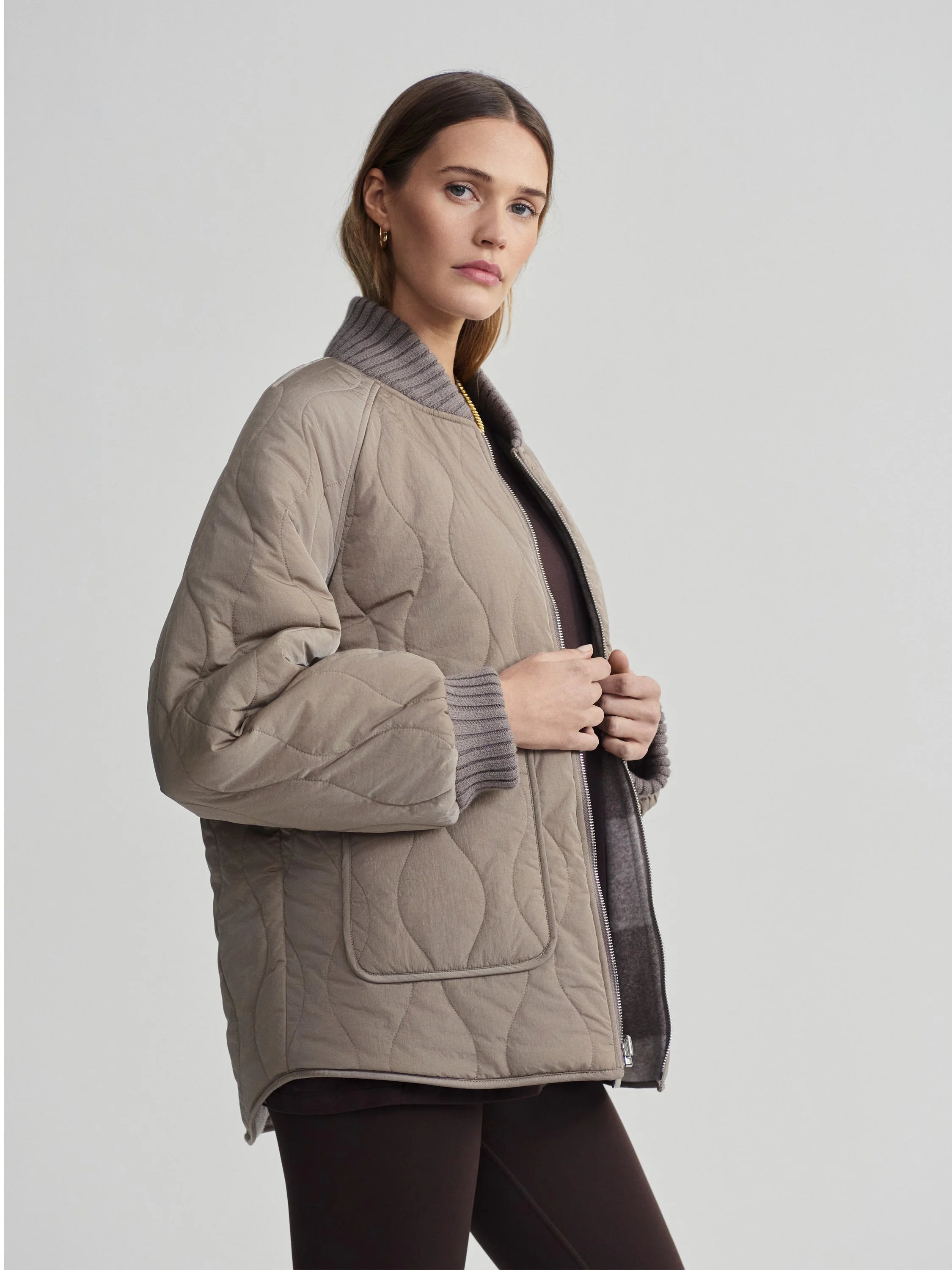 Greige wavy quilted jacket with ribbed grey collar and cuffs, unzipped to show a dark brown reverse side.