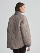Muted brown quilted jacket with wavy stitching. Features grey ribbed collar & cuffs.