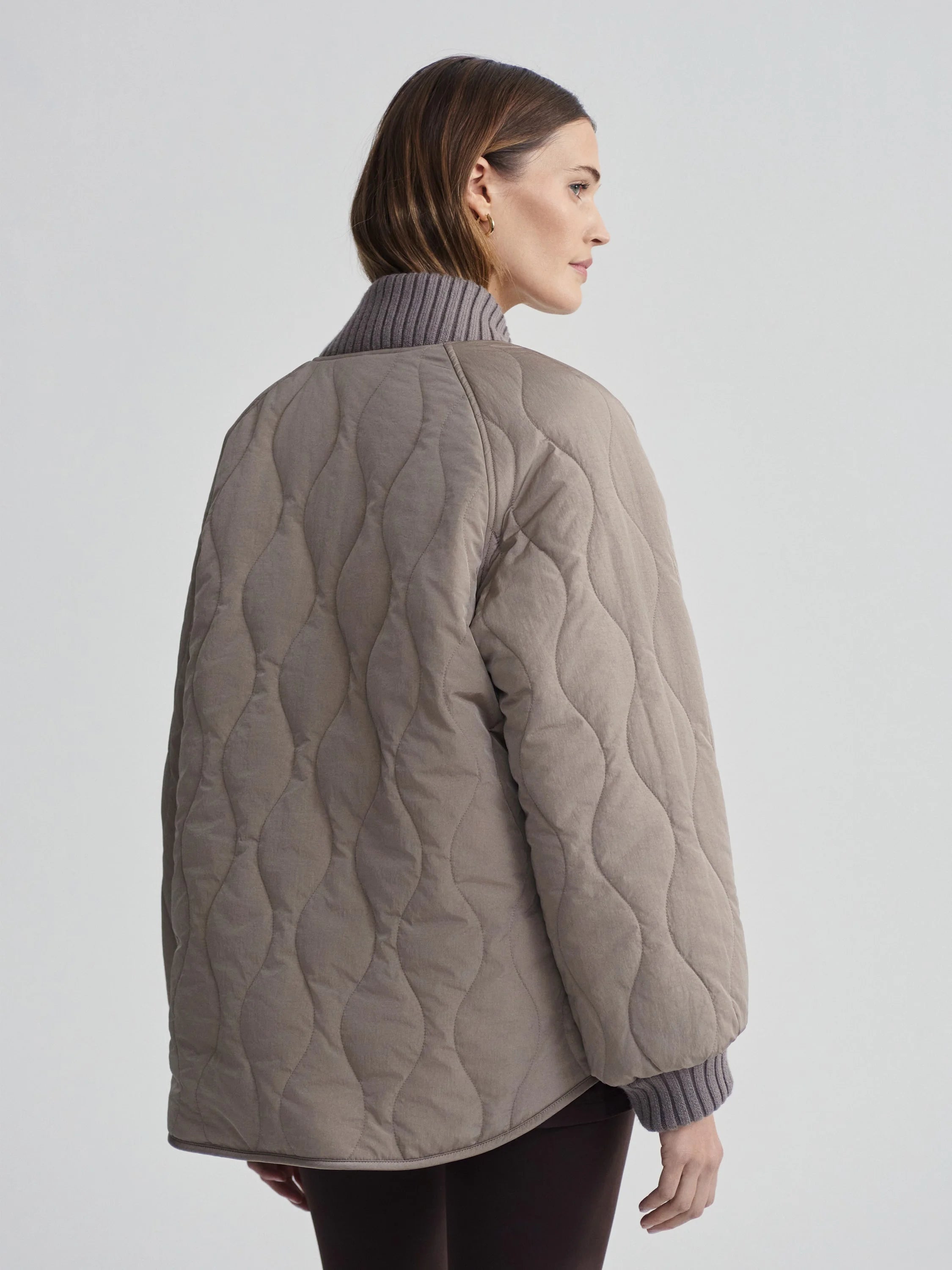 Muted brown quilted jacket with wavy stitching. Features grey ribbed collar & cuffs.