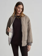 Taupe quilted reversible jacket with wavy stitching; reverse side reveals grey and white large check pattern.