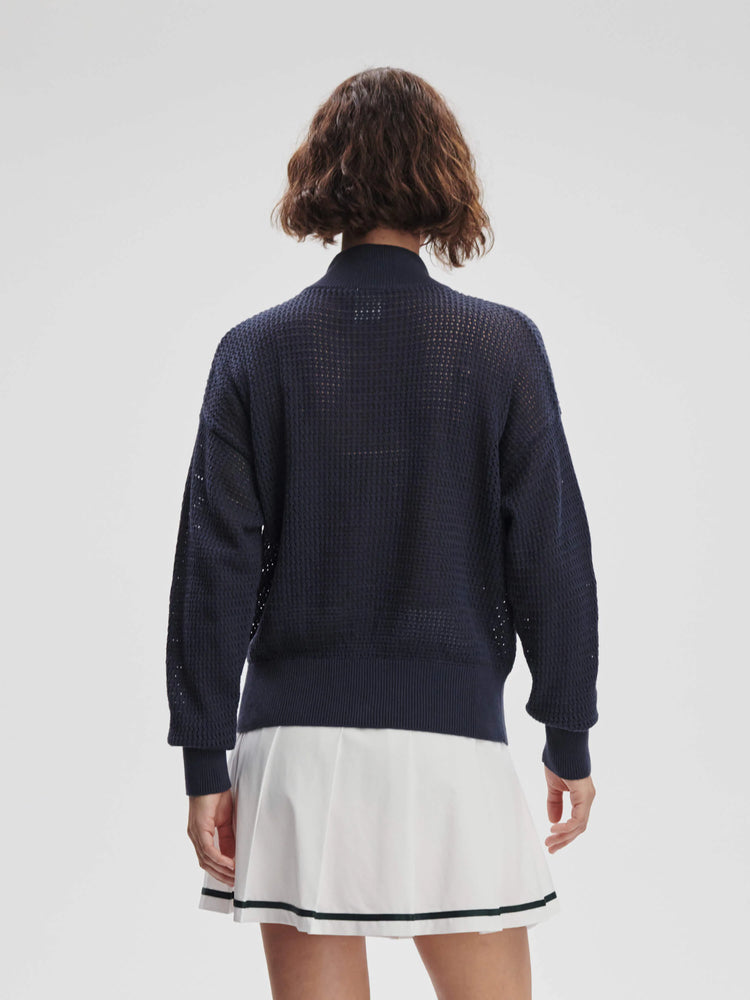 Navy blue waffle knit sweater, back view. Features a ribbed high collar, cuffs, and hem. The fabric is semi-sheer.