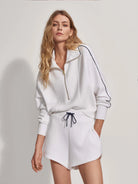 White high-rise shorts with navy drawstring and trim.  Matching white zip-up top with navy trim.