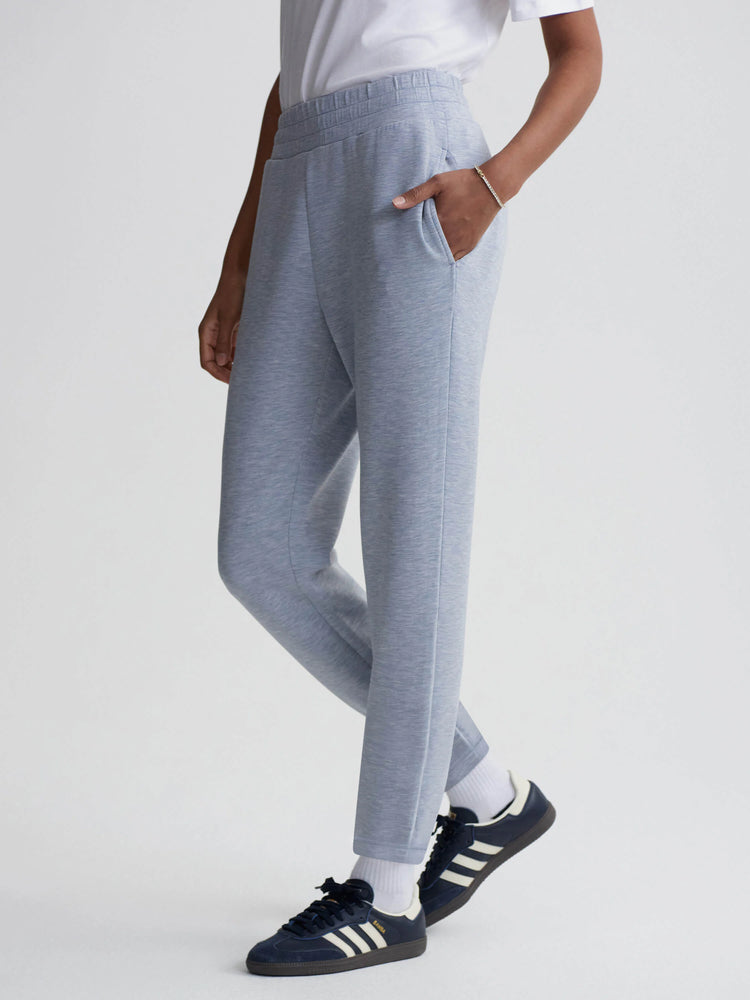 Light blue, slim-fitting pants with an elastic waistband and pockets.  The pants are shown on a model.