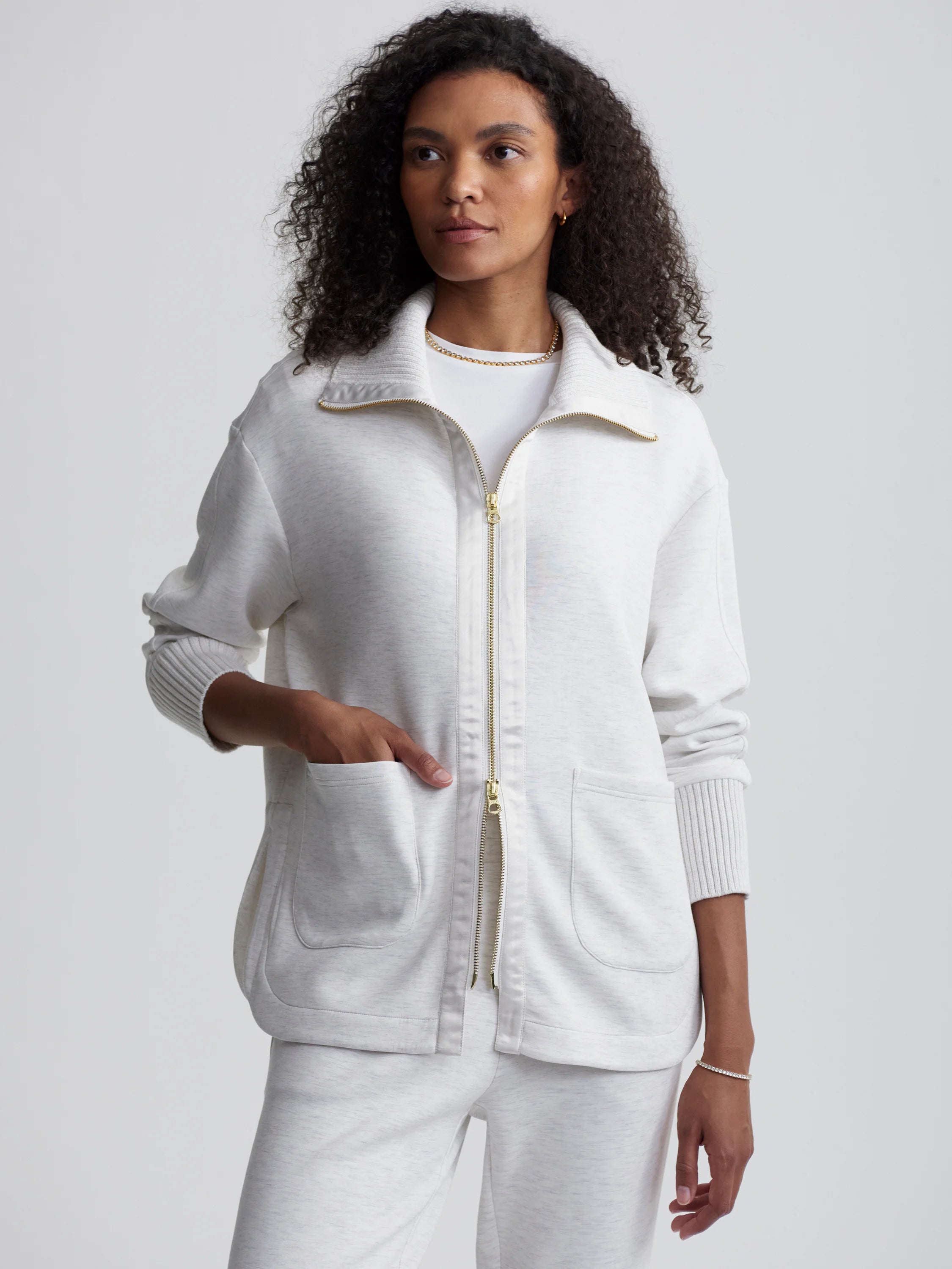 Off-white zip-through jacket with ribbed cuffs and patch pockets. Gold zipper.