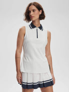 White ribbed sleeveless top with navy collar and half-zip. Model also wears a pleated white and navy skirt.