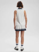 Here's alt text for the image, under 125 characters:

White ribbed sleeveless top with navy trim, paired with a white...