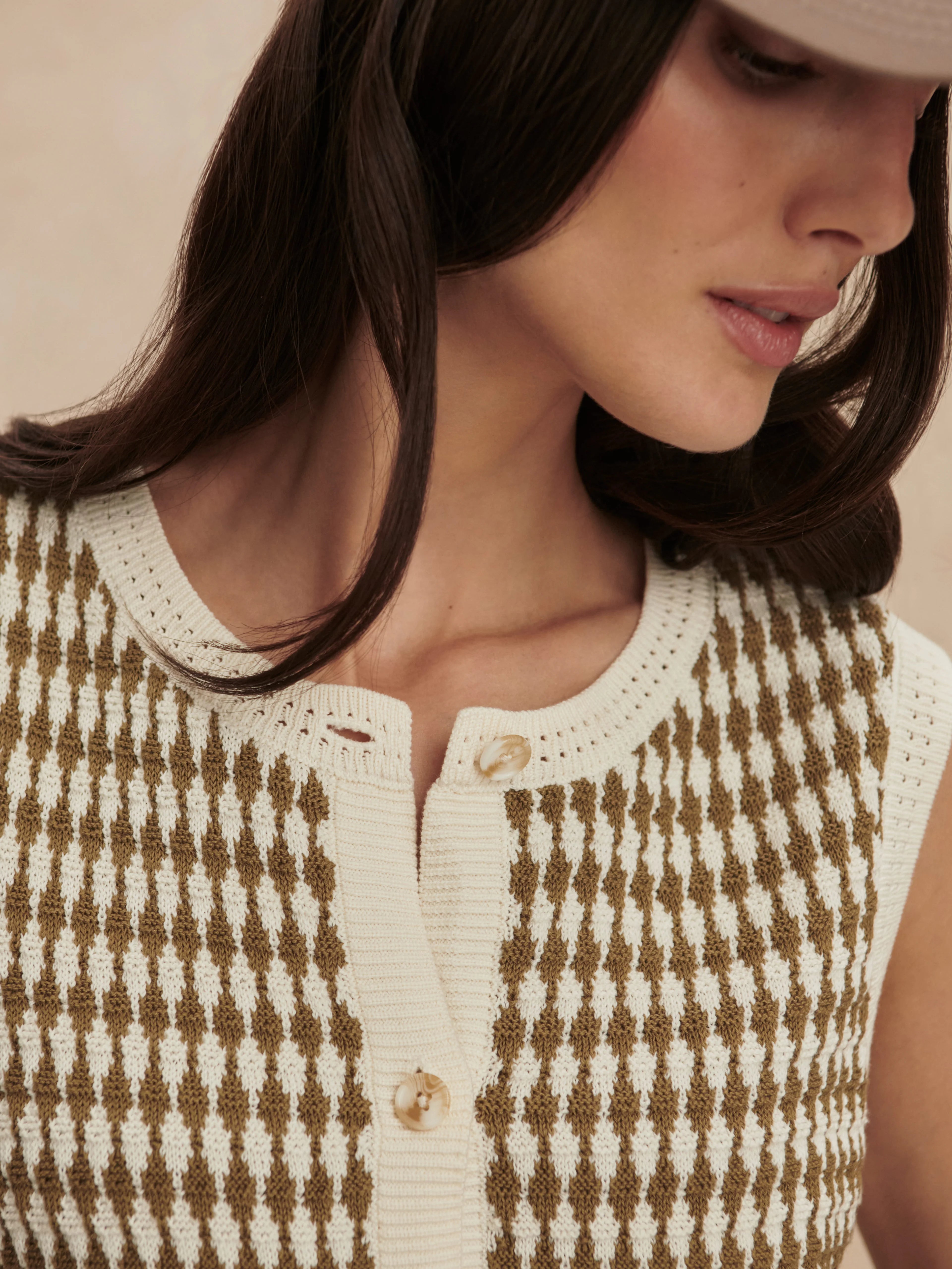 Cream and olive brown knit vest with a diamond pattern, round neck, and button-front closure.