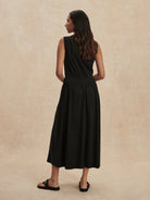 Black sleeveless maxi dress with an elasticated waist and flowing skirt, shown from the back.
