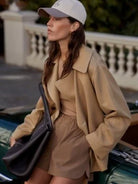 Light beige short trench coat with wide lapels and a relaxed fit, worn open.