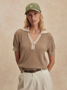 Tan ribbed knit short-sleeve polo with cream collar, v-neck, and single button closure.