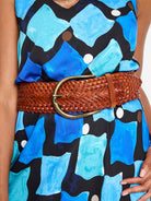 Wide, cognac woven leather belt with intricate braiding and an antique brass oval buckle.