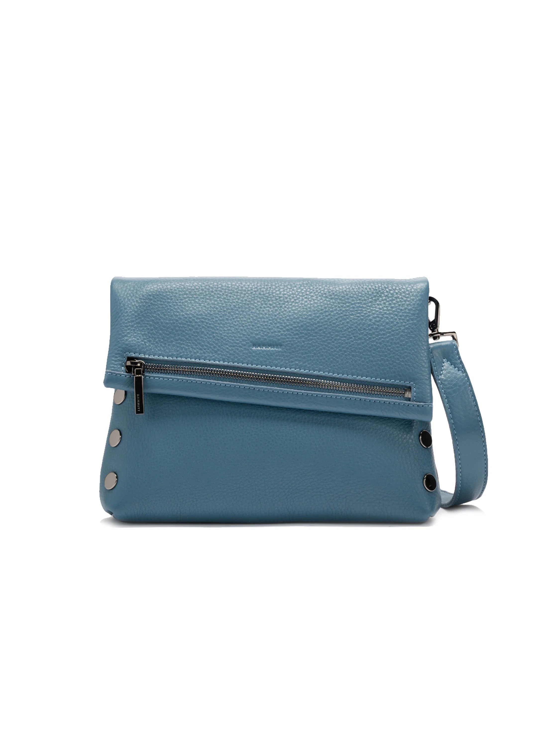 Dusty blue pebbled leather fold-over bag with silver zipper, round studs, and a matching shoulder strap.