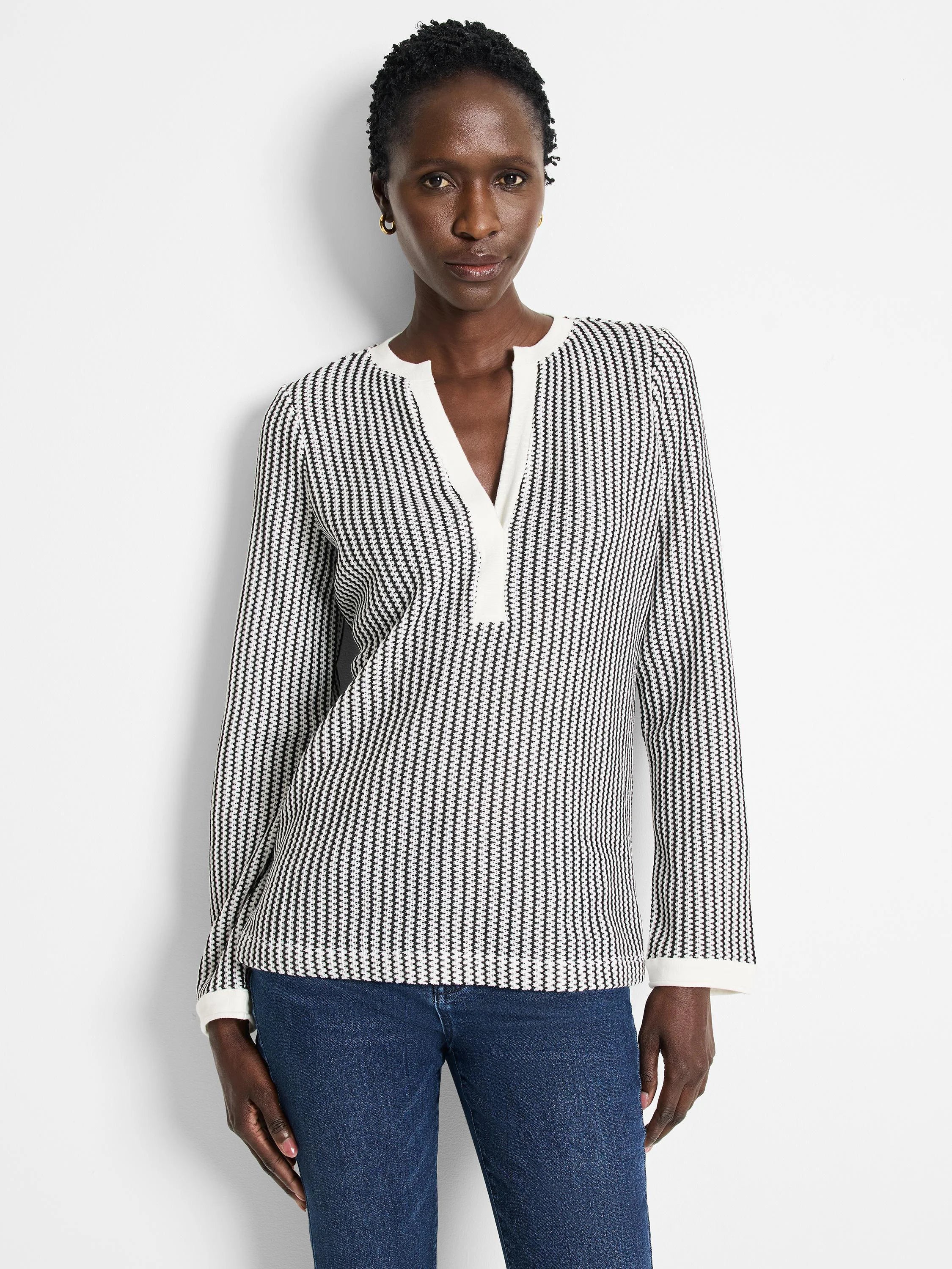 Off-white top with thin black vertical stripes, split neckline, long sleeves, and off-white cuffs.
