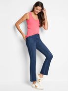 Coral pink ribbed knit scoop neck tank top worn by a model, tucked into jeans.