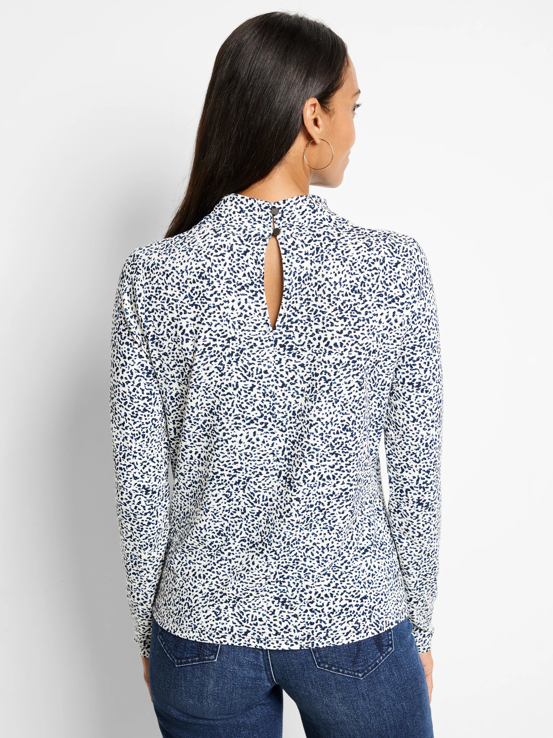 Cream-colored top with dark blue speckled pattern, high neck, keyhole back. Long sleeves.