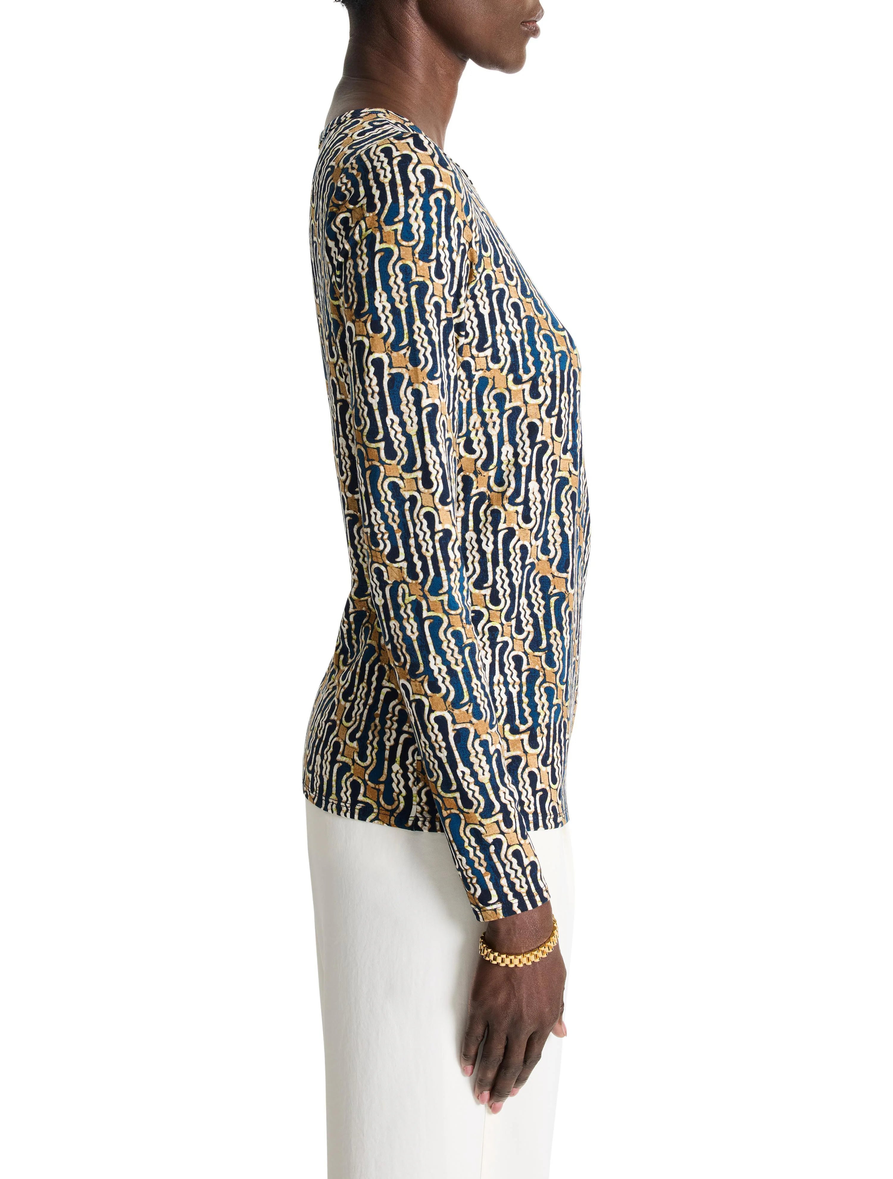 Long-sleeved, form-fitting top. Teal, beige, and white abstract batik print.  Side profile view.